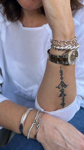 Woman arm wearing sterling silver bracelet stacked inamullumani Arabic Tatoo on arm 