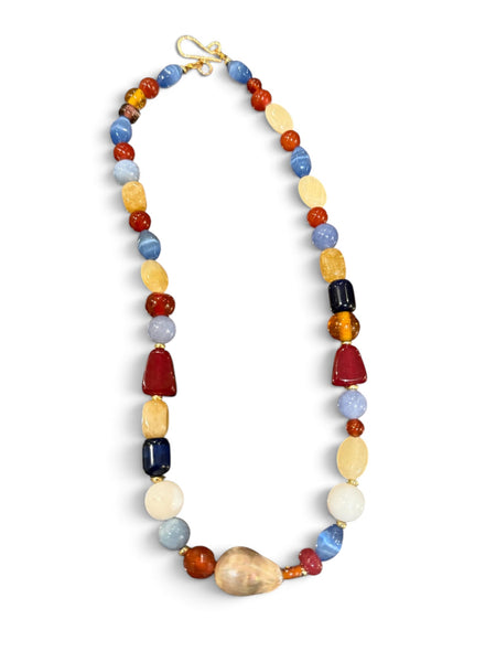 Colourful gemstone and baroque pearl necklace with blue, rust-red and pale yellow beads on a white background inamullumani 