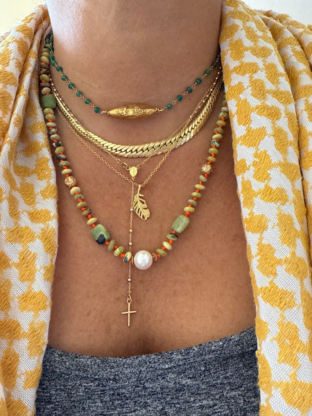 Close-up of a person's neck wearing multiple necklaces with a yellow and white patterned fabric background.
