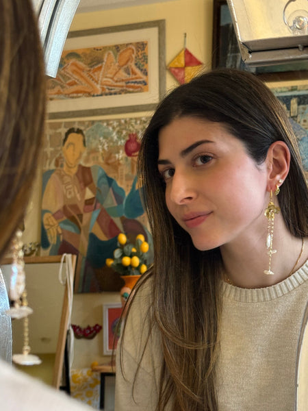 Woman looking into a mirror with a decorative wall in the background inamullumani 