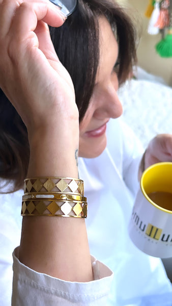 Woman with hand on head and 3 stacked gold bracelets with tribal geometric design inamullumani oakville 