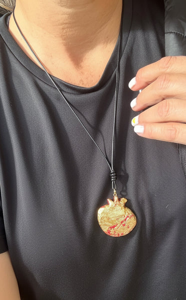 Person wearing a necklace with a gold pendant on a plain background