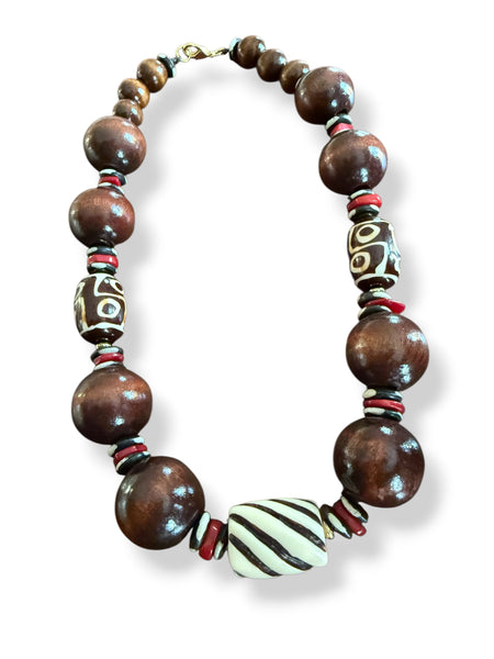 Necklace with chunky wooden beads and red coral  accents on a white background inamullumani