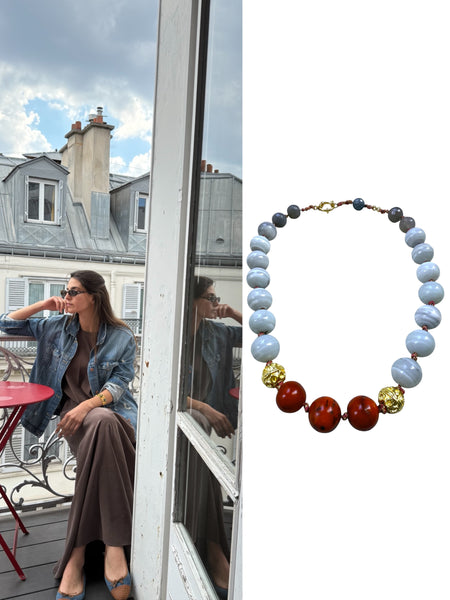 Woman sitting outdoors with a scenic background of Paris, next to a close-up of a beaded necklace with blue, red, and gold beads. Inamullumani 