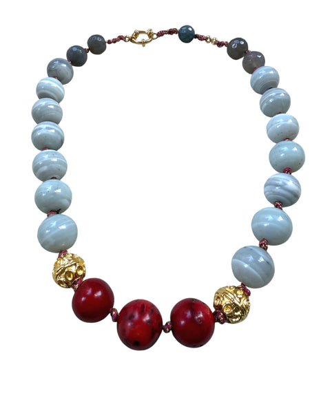 Necklace with blue grey, red, and gold beads on a white background inamullumani 