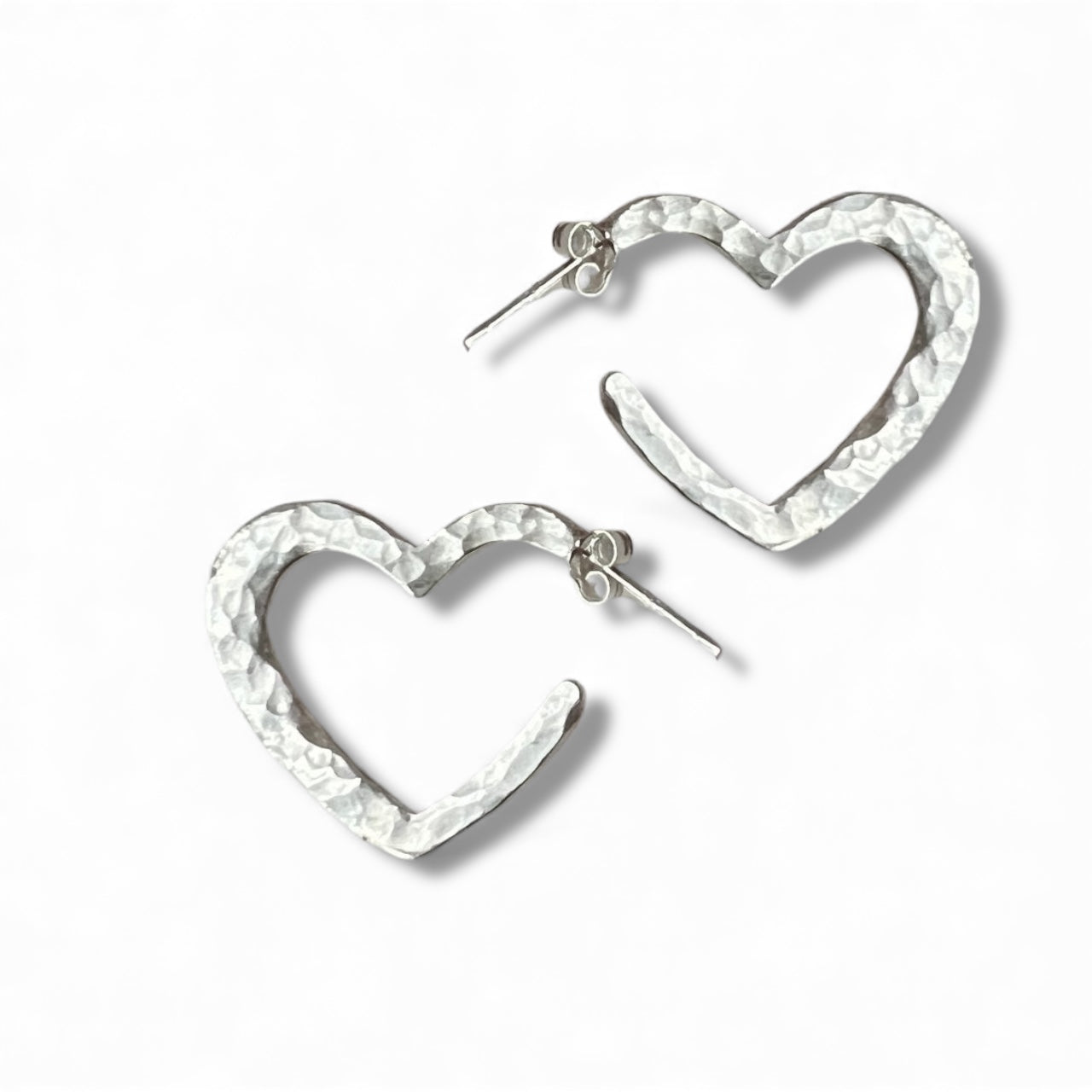 Heart-shaped silver earrings on a white background inamullumani