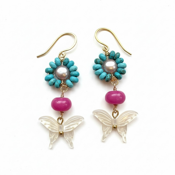 Pair of earrings with turquoise and pink beads and butterfly charms on a white background