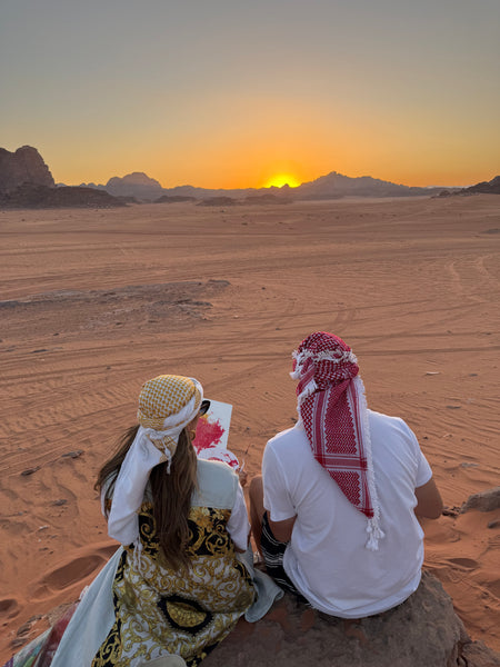 Person in traditional attire with a child in Wadi Rum  a desert setting at sunset. 
