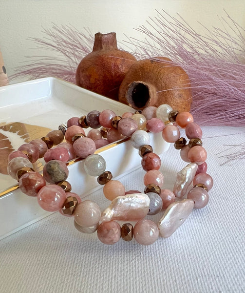 Beaded bracelets on a textured surface with a decorative vase in the background