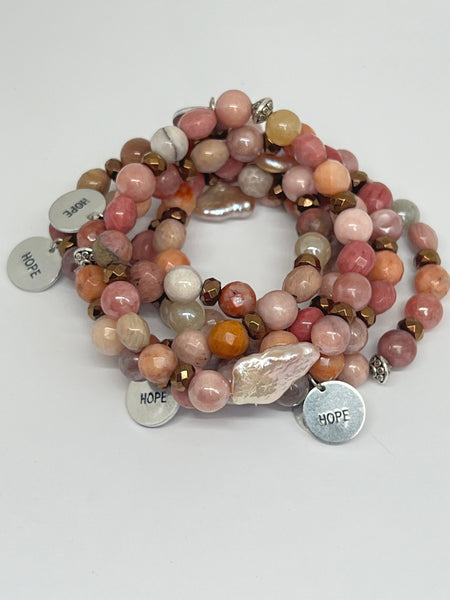 Stack of beaded bracelets with 'HOPE' charms on a white background inamullumani