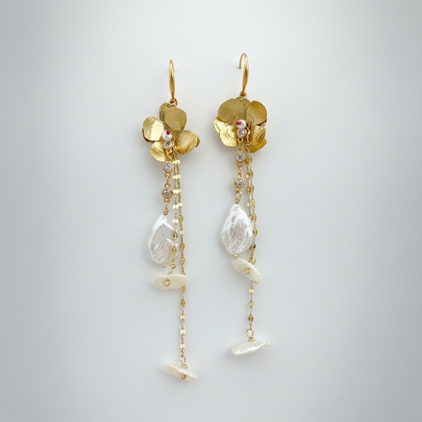 Gold floral earrings with pearl-like stones on a light gray background inamullumani 