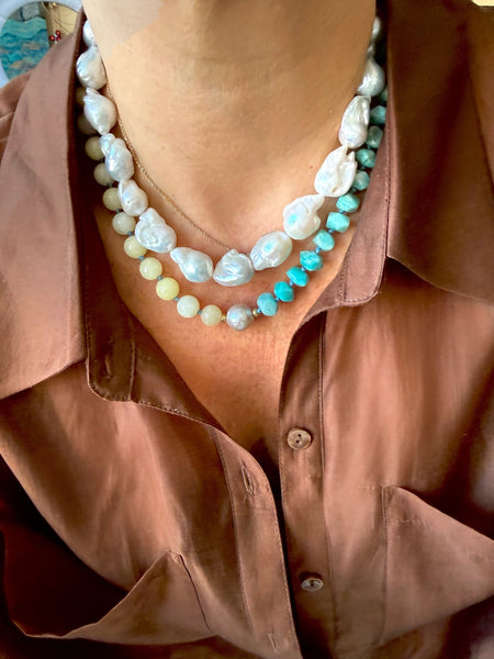 Two Necklaces with chunky baroque pearls and Amazonite  beads worn by a person in a brown shirt.
