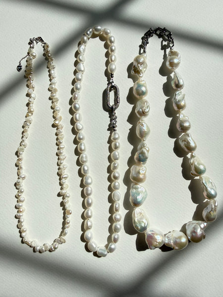 Three pearl necklaces of different lengths on a light background inamullumani