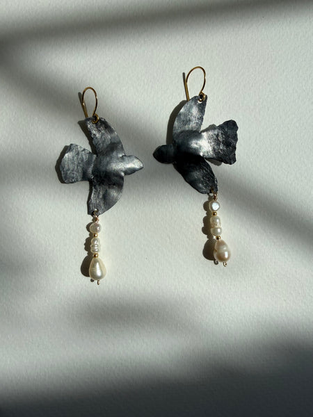 Pair of earrings with Pigeon dove design and pearl accents on a light gray background