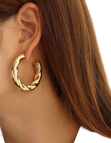 Gold hoop earring worn by a person with brown hair on a white background