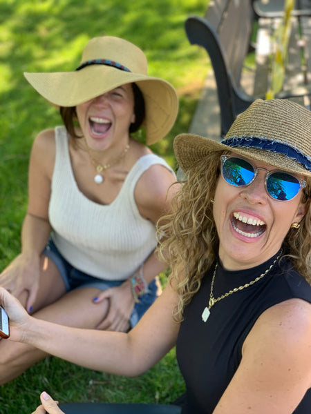 Stylish women wearing gold chain necklace and hats in the park laughing 