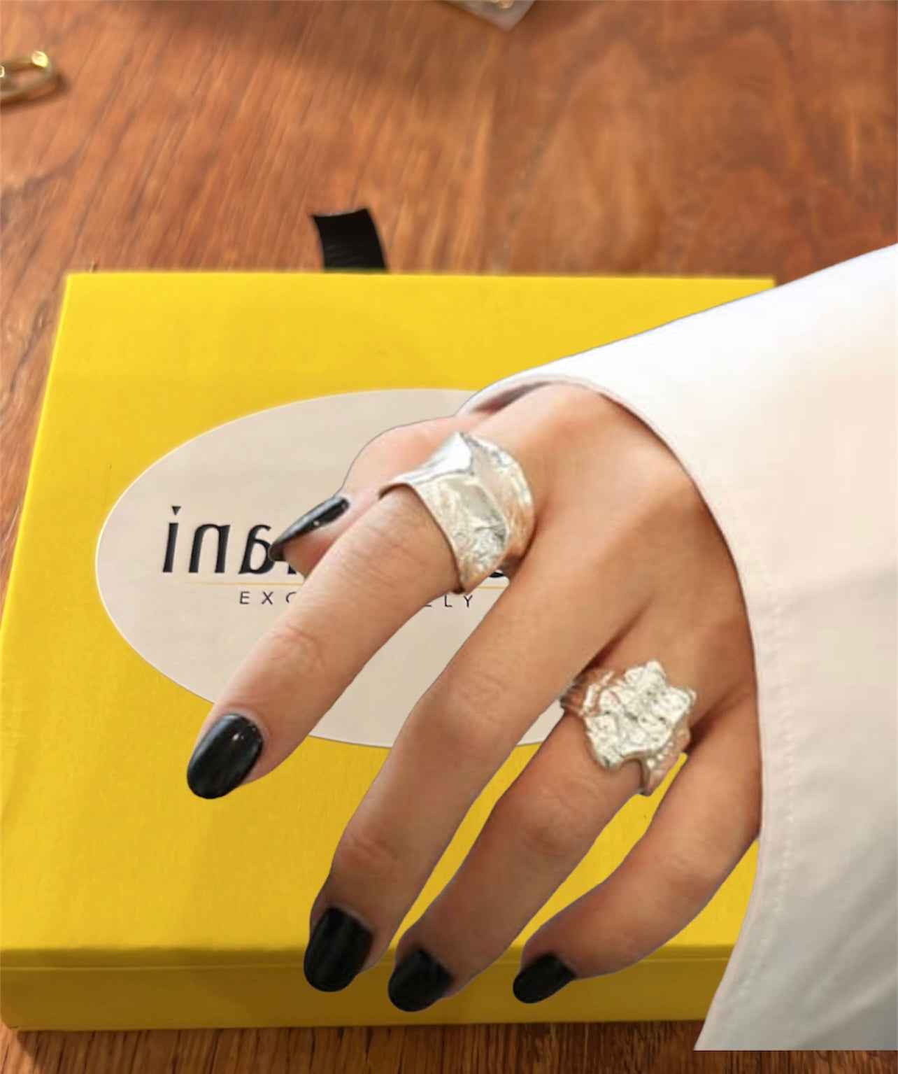 Female hand wearing sterling silver rings holding inamullumani yellow box