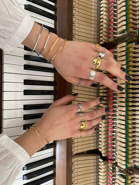 Stack of rings silver and gold plated on hands playing piano 