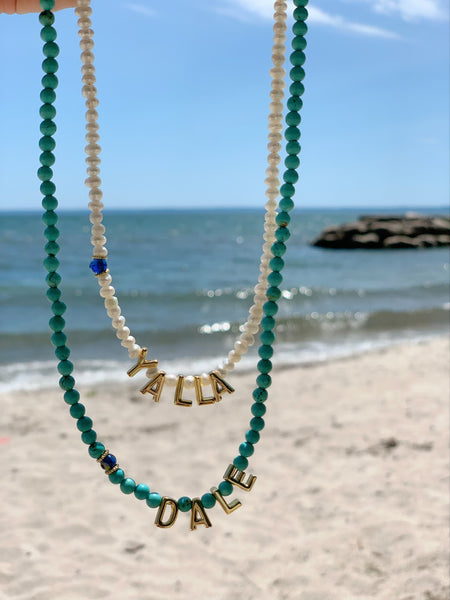 Yalla necklace with white pearls and Dale with turquoise showing on the beach 